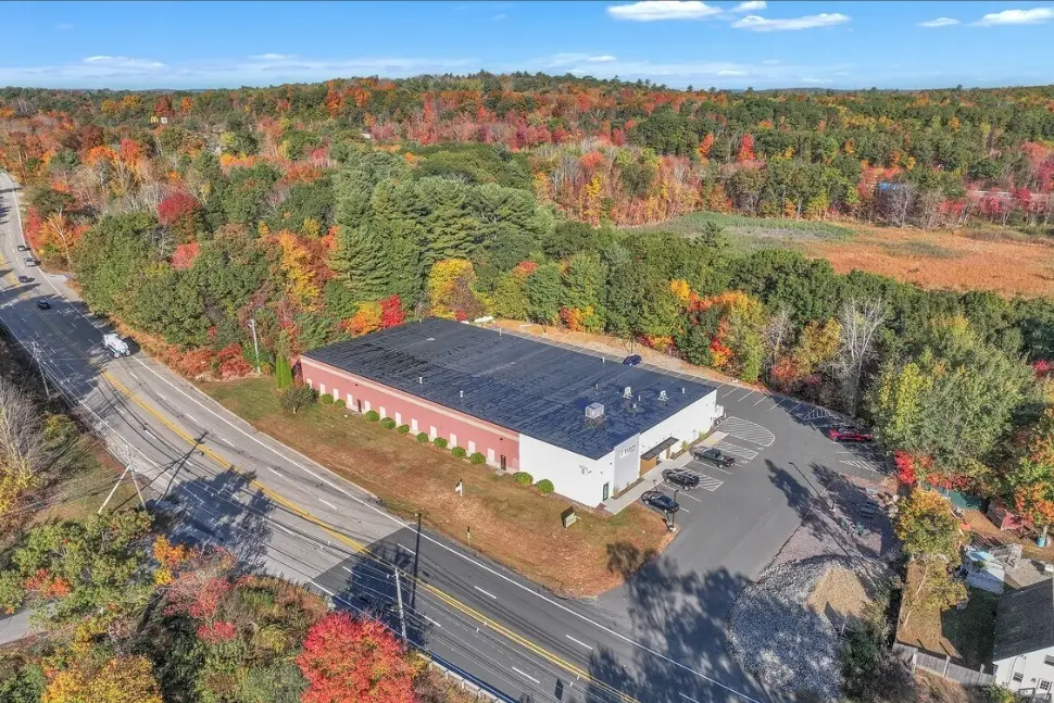 Aerial view of the brick warehouse at 144 Sturbridge Road beside Route 20, surrounded by autumn trees