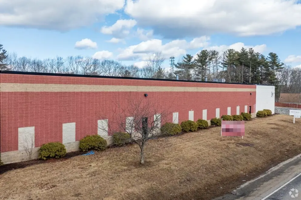 Brick facade along Route 20 with a for lease sign on the lawn