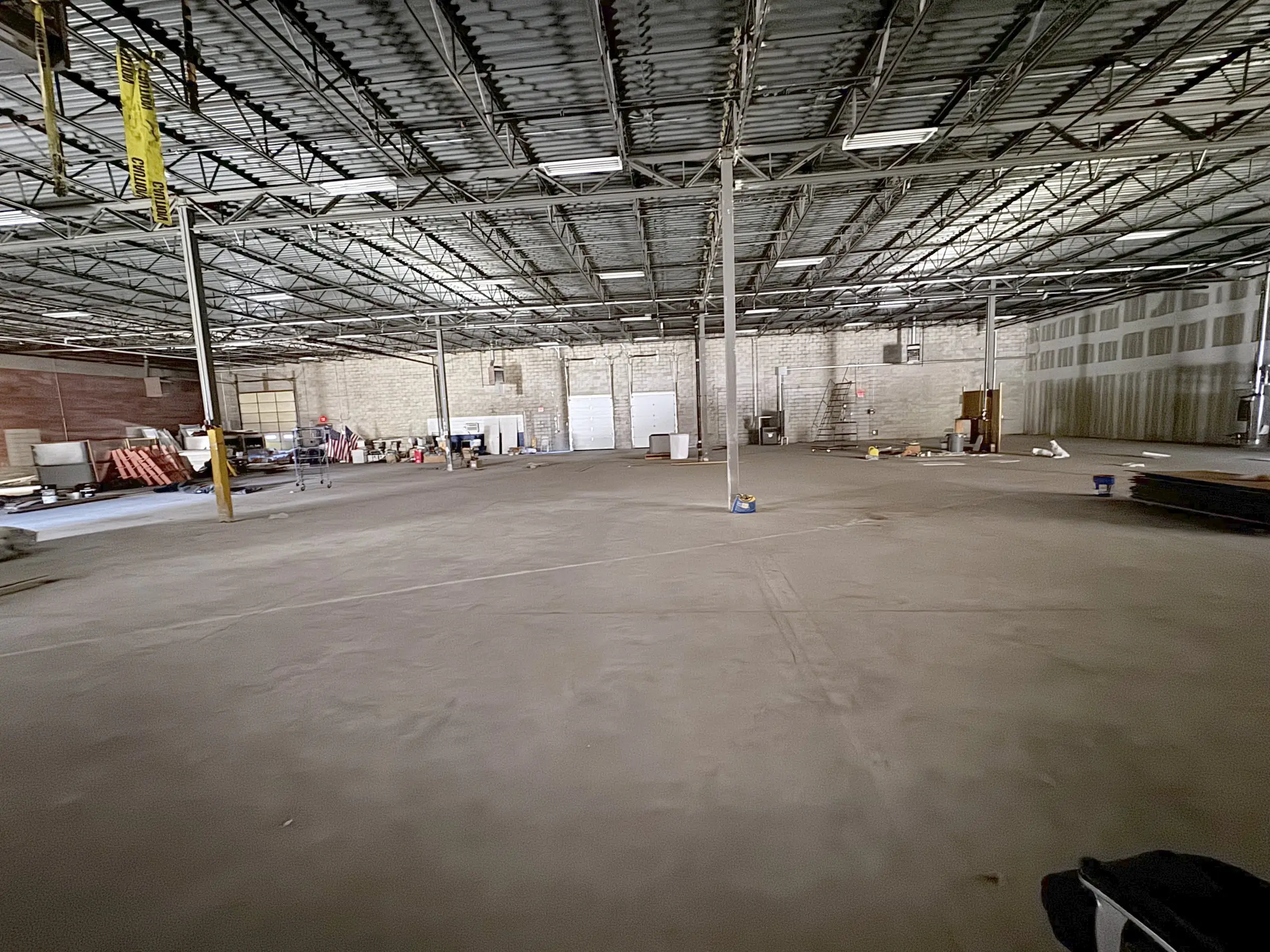 Wide view of the empty warehouse floor with steel roof joists and lighting